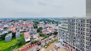 A residential area with a mix of houses and a large building with balconies. - Homey And Elegant Studio Amazana Serpong Apartment (South Tangerang)