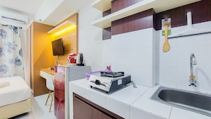 A compact kitchen with a stove, sink, and a small dining area. - Homey And Elegant Studio Amazana Serpong Apartment (South Tangerang)