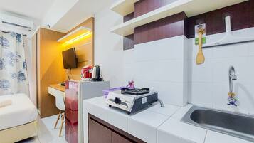 A compact kitchen with a stove, sink, and a small dining area.
