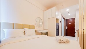 Ein Hotelzimmer mit einem großen Bett, einem runden Spiegel, einem Nachttisch und einer Holztür.