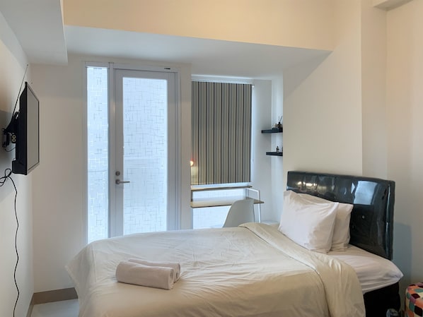 Relax in a stylish room with a large bed, TV, and window with a city view.