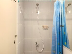 Enjoy a refreshing shower in this bathroom with a handheld showerhead and convenient soap dish.