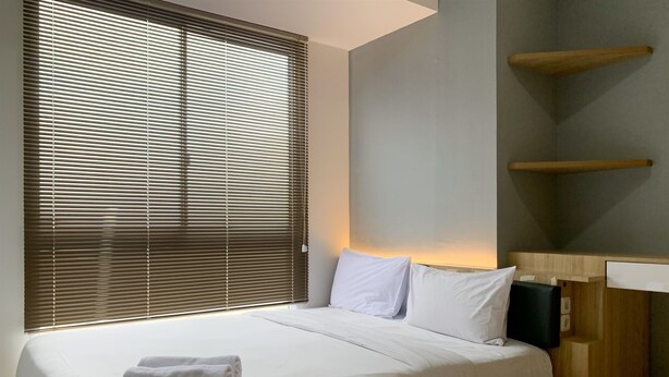Una camera da letto moderna con un letto grande, un comodino in legno, una libreria a muro e una finestra con persiane.