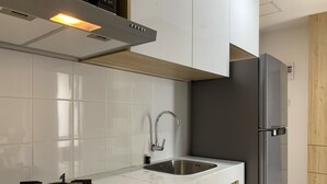 Una cucina moderna con mobili bianchi, un lavandino in acciaio inossidabile e un piano cottura a induzione nero.