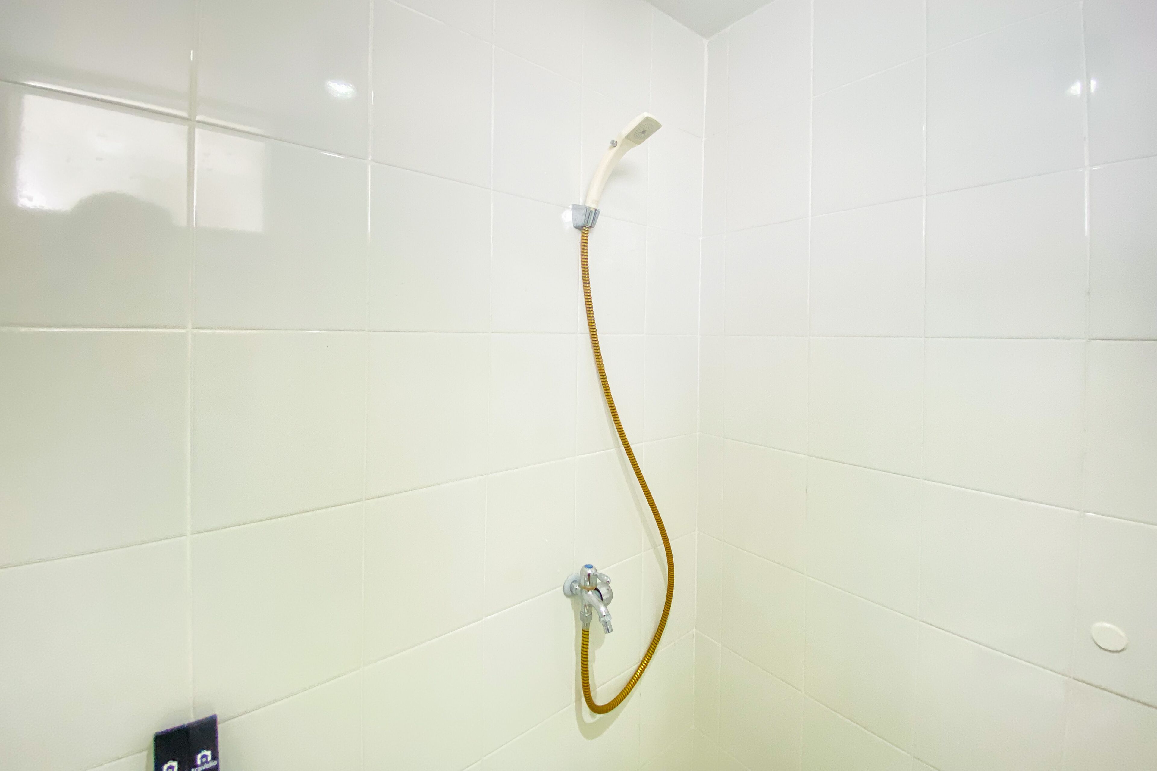 A shower with a handheld hose in a tiled bathroom.