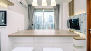 Une cuisine moderne avec un plan de travail en bois, des meubles blancs et un téléviseur encastré.