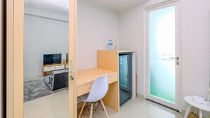 Una habitación pequeña con escritorio, silla y un refrigerador.