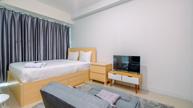 Una habitación de hotel moderna con cama, televisor, sofá y un escritorio pequeño.