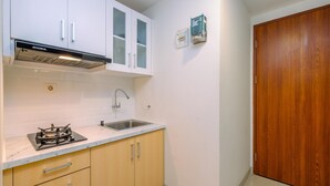 Una cocina con armarios blancos, una estufa a gas, un fregadero y una puerta de madera.