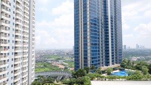 A high-rise building with a modern design, featuring a large glass facade and multiple balconies. - Good Studio Connected To Mall At Orchard Supermall Mansion Apartment (Surabaya)