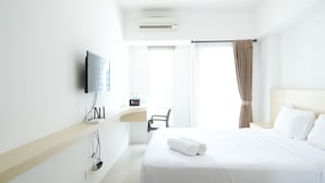 A hotel room with a bed, a desk, a chair, a television, and a window with curtains. - Good Studio Connected To Mall At Orchard Supermall Mansion Apartment (Surabaya)