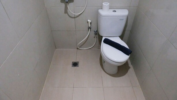 A small, tiled bathroom with a toilet, a bidet, and a toilet paper holder. - Good Studio Connected To Mall At Orchard Supermall Mansion Apartment (Surabaya)