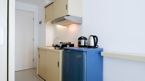 A compact kitchenette with a blue refrigerator, a kettle, and a stove. - Good Studio Connected To Mall At Orchard Supermall Mansion Apartment (Surabaya)