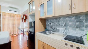 A compact kitchen with wooden cabinets, a tiled backsplash, a sink, and a stove. - Good And Clean Studio Room Serpong Greenview Apartment (South Tangerang)