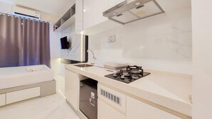 A compact kitchen with a built-in stove, a sink, and a compact refrigerator. - Studio Full Furnished With Comfort Design At Sky House Bsd Apartment (Pagedangan)
