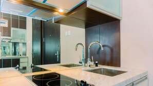 A modern kitchen with a double sink, an induction cooktop, and a stainless steel faucet. - Homey And Minimalist Studio Room At Gp Plaza Apartment (Jakarta)