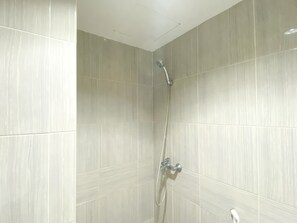 A shower with a handheld showerhead and a wall-mounted faucet.