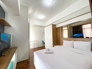 A hotel room with a bed, a TV, a desk, and a mirror.