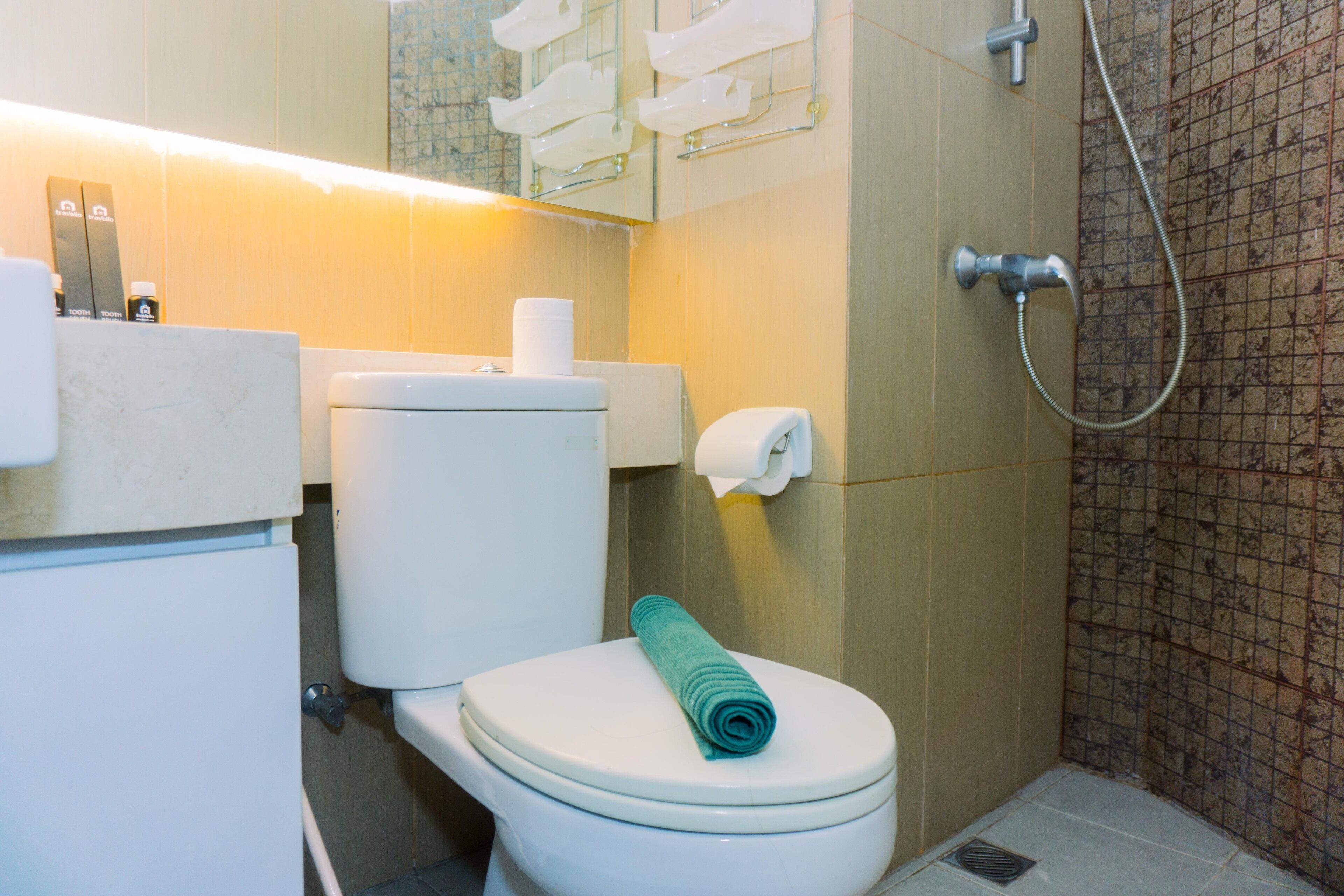 A bathroom with a toilet, a towel, a shower, and a mirror.