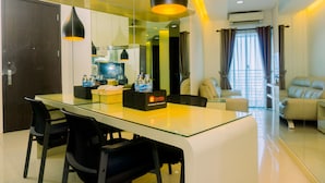 Een moderne hotelkamer met een glazen eettafel, zwarte stoelen, een bank en een grote spiegel.