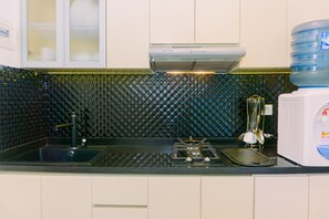A kitchen with a black countertop, a stove, a sink, and a water dispenser.