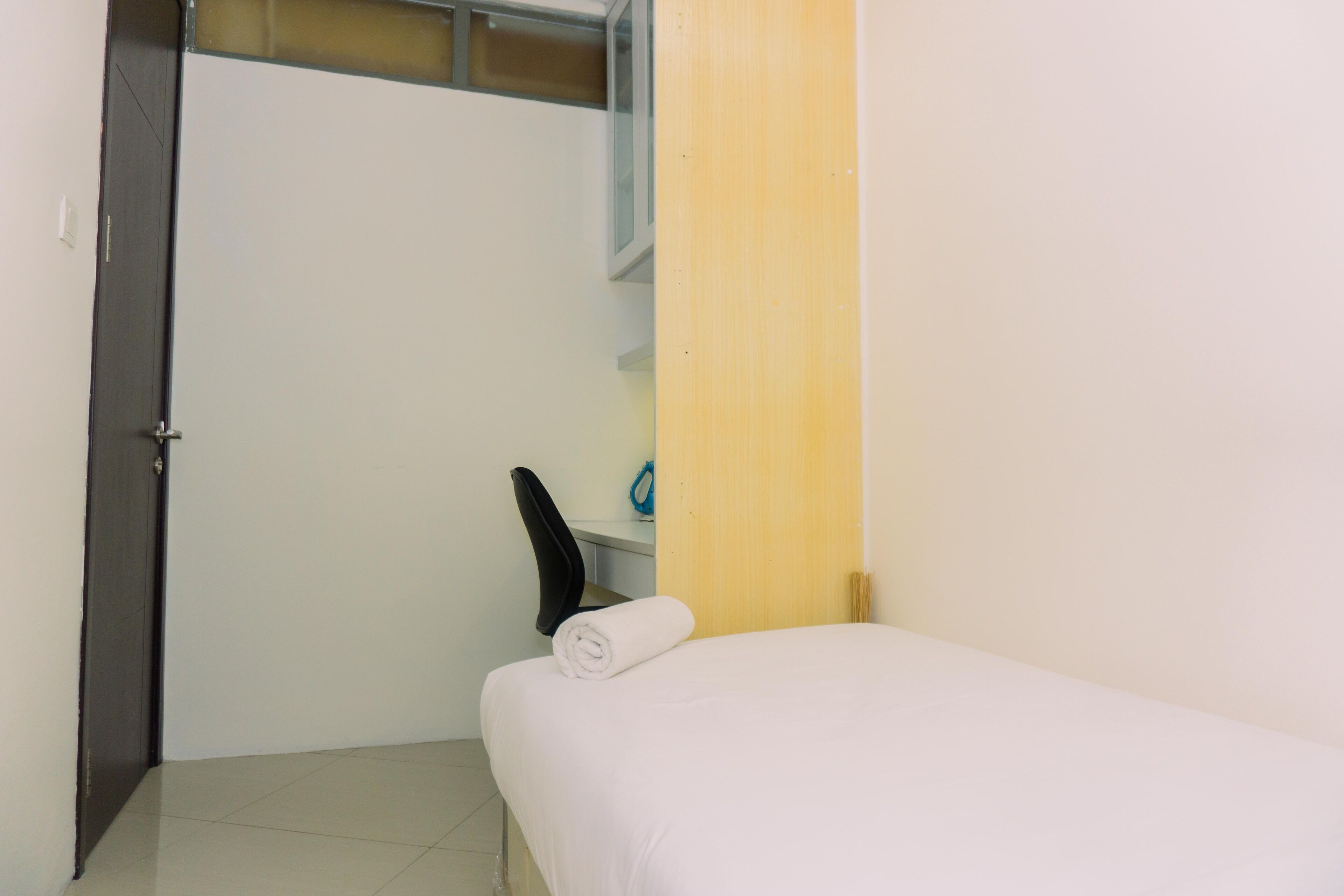 Una habitación pequeña y limpia con una cama, un escritorio y una silla.