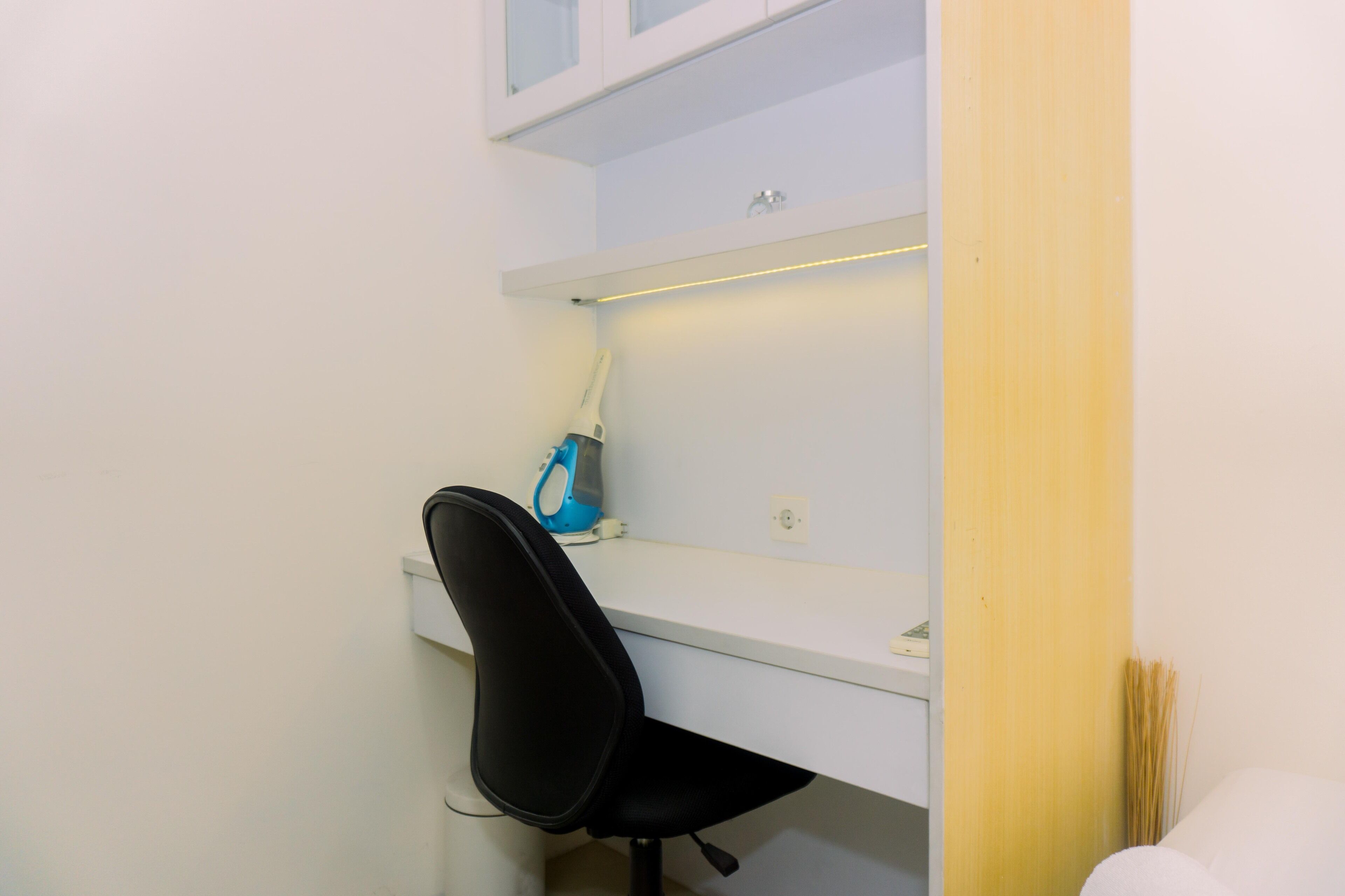 A small, clean office space with a white desk, a black office chair, and a blue printer.