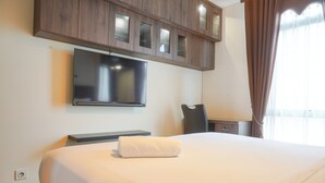 Ein Hotelzimmer mit Bett, einem Flachbildfernseher an der Wand, einem Schreibtisch und einem Stuhl.
