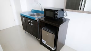 A compact kitchen with a sink, a microwave, and a small refrigerator. - Comfy And Modern Studio (No Kitchen) At Orchard Supermall Mansion Apartment (Surabaya)