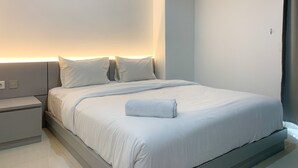 Ein modernes Schlafzimmer mit einem großen Bett, einem Nachttisch und einer Wandleuchte.