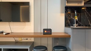 Eine moderne Küche mit Flachbildfernseher, einer travelio-Box und zwei Barhocker.
