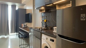 Eine moderne Küche mit Einbauwaschmaschine, einem Edelstahlkühlschrank und einem flachbildfernseher an der Wand.
