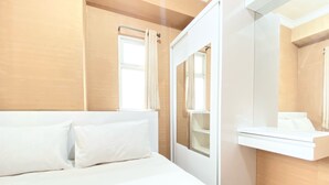 A modern hotel room with a bed, a small window, and a mirror above the sink. - Modest 2Br Apartment At Suites @Metro (Bandung)