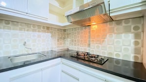 A kitchen with white cabinets, a black countertop, and a patterned backsplash. - Modest 2Br Apartment At Suites @Metro (Bandung)