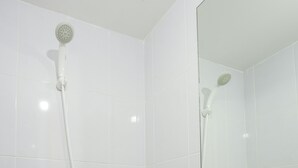 A bathroom with white tiles and a shower with a handheld showerhead. - Simply And Cozy Living Studio At Tokyo Riverside Pik 2 Apartment (Teluknaga)