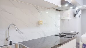 A modern kitchen with a marble backsplash, stainless steel sink, and a gas stove. - Simply And Cozy Living Studio At Tokyo Riverside Pik 2 Apartment (Teluknaga)