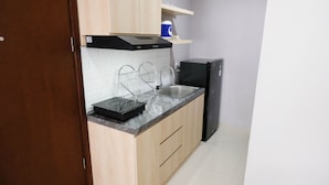 A compact kitchen with a black range hood, a sink, and a refrigerator.