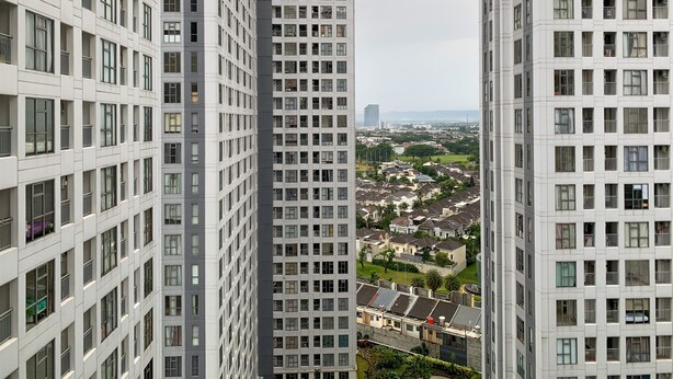 Un immeuble de grande hauteur, doté d’une façade à motifs géométriques de fenêtres et de balcons, entouré d’autres bâtiments similaires.