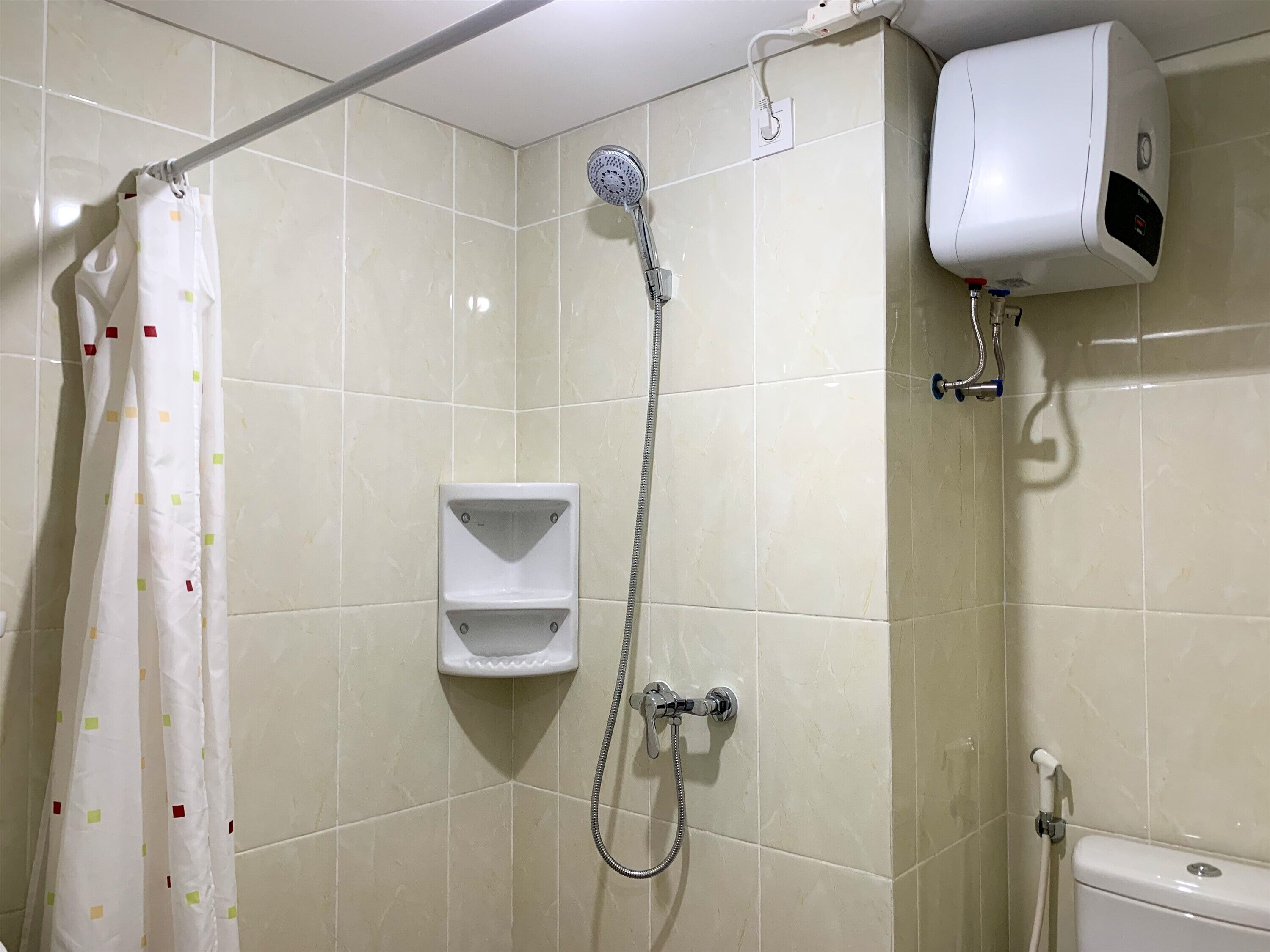 Un espace douche équipé d’un pommeau de douche à main, d’un porte-serviettes et de toilettes.