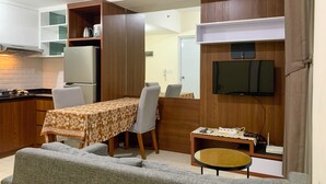 Un espace de vie compact comprenant un coin cuisine, un coin repas, un canapé et un téléviseur fixé au mur.