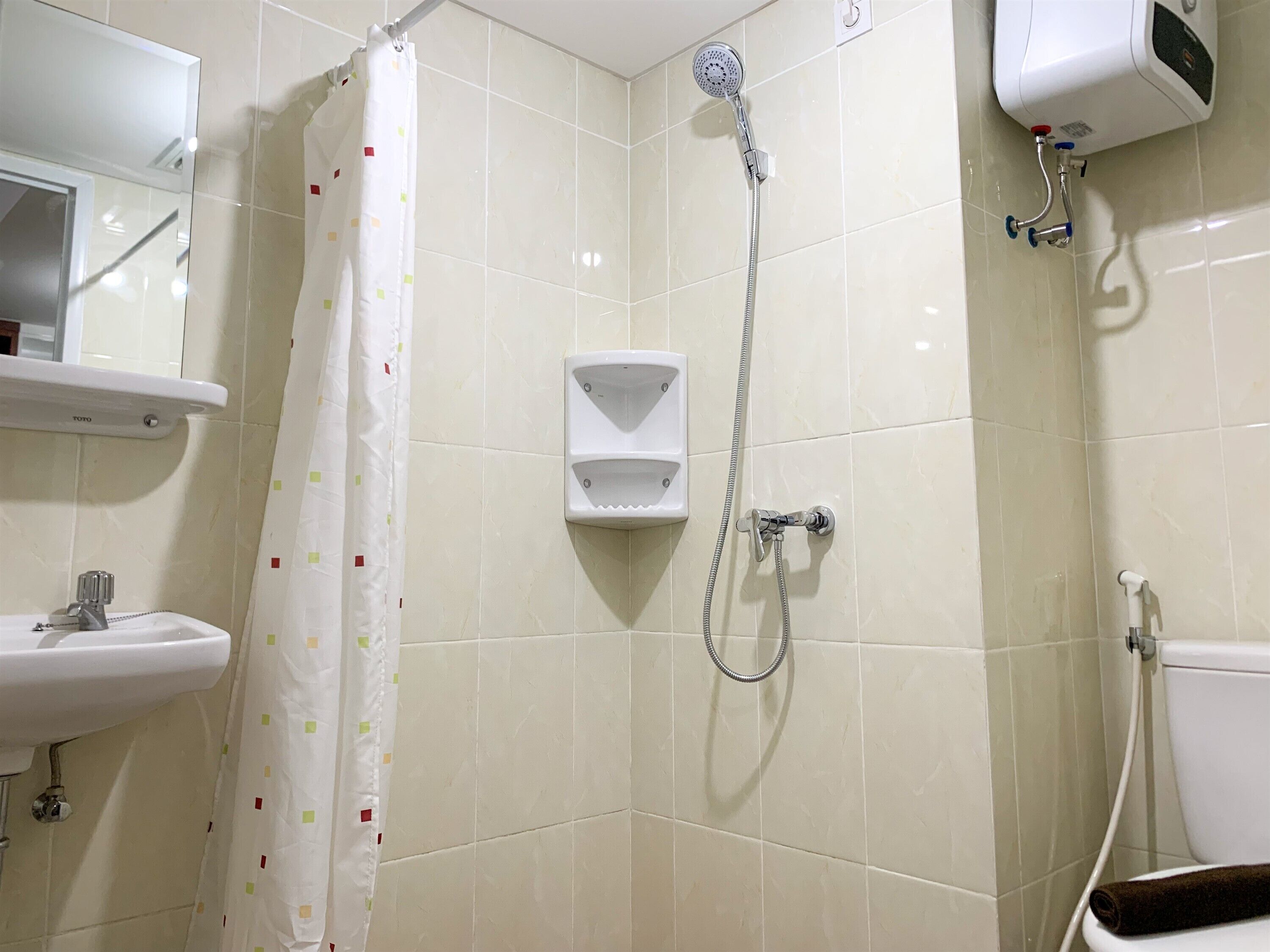 A bathroom with a shower, toilet, sink, and a towel rack.