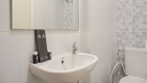 A bathroom with a white sink, a mirror, and a tiled shower area.