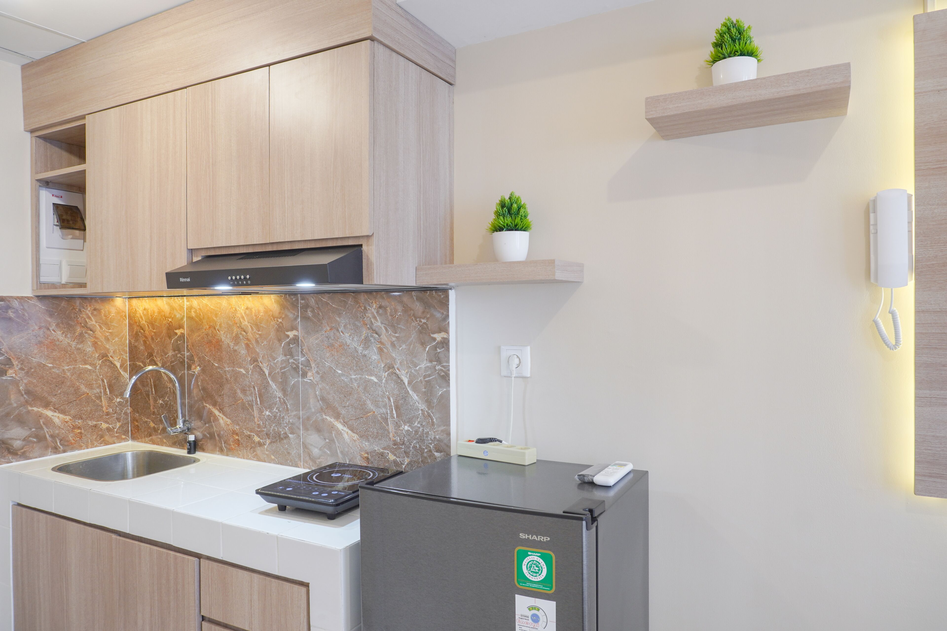 A modern kitchen with a built-in stove, a sink, wooden cabinets, and a refrigerator.