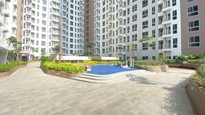 A residential building with multiple floors, balconies, and a landscaped courtyard with a pool.