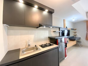 A modern kitchen with a stainless steel sink, gas stove, and black cabinets.