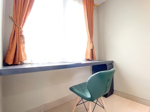 A room with a window, a chair, and a shelf.