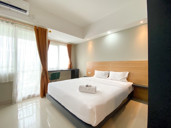 A hotel room with a large bed, a desk, and a chair.