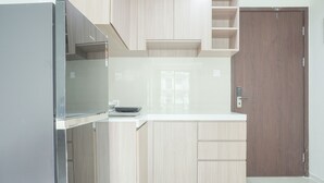 Una cocina con armarios de madera clara, encimera blanca y puerta de madera oscura.