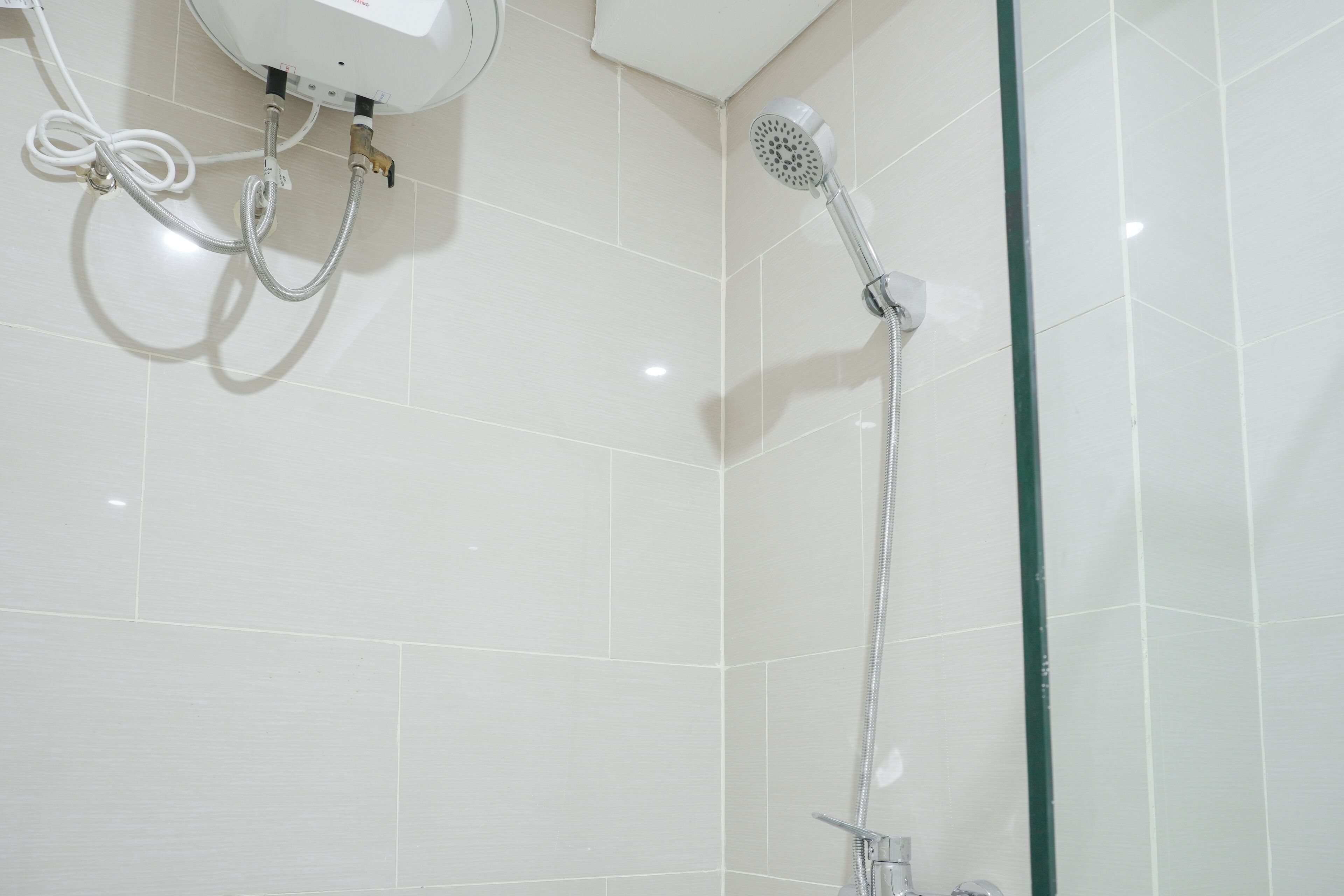 A shower with a handheld showerhead and a wall-mounted faucet.
