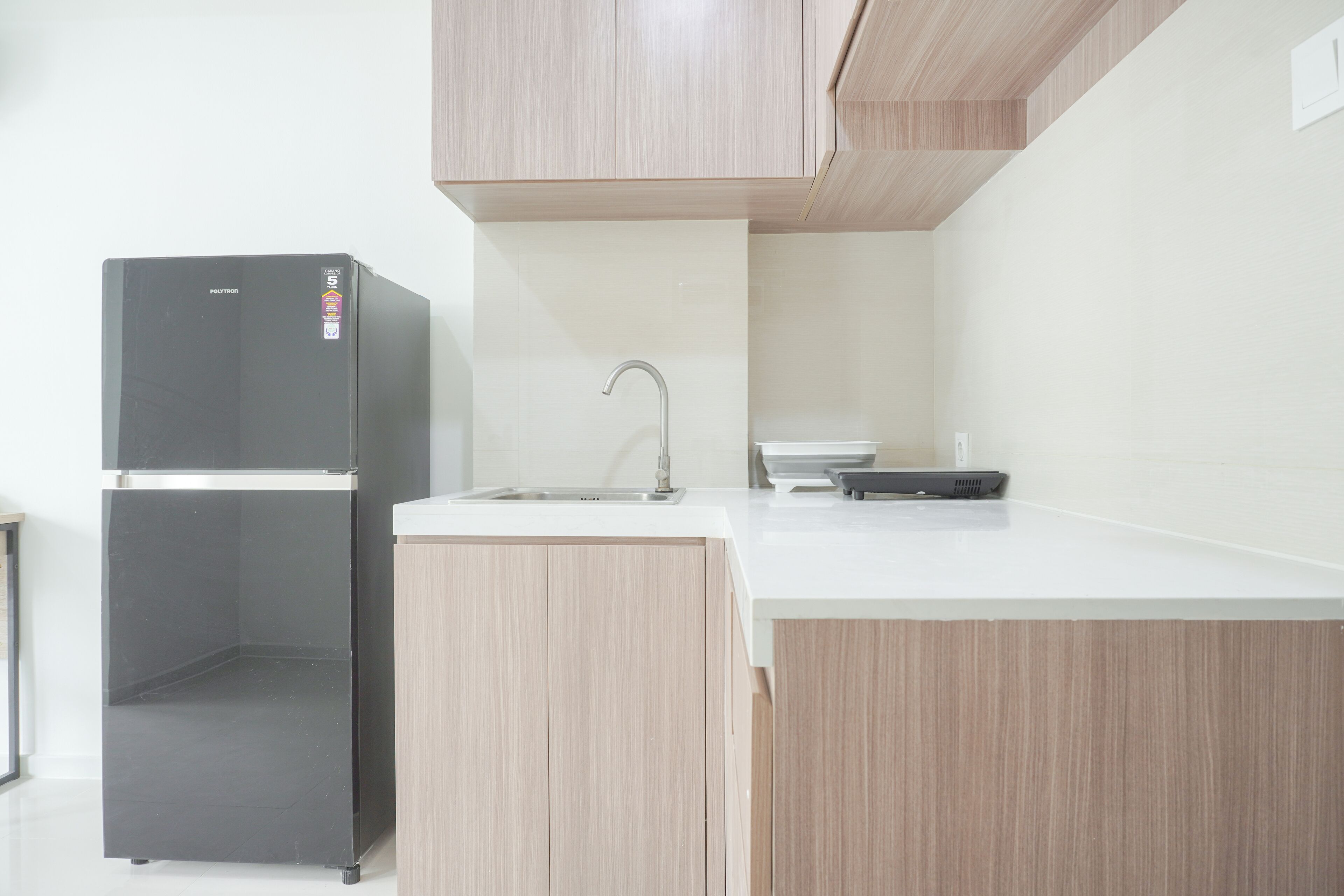 A kitchen with a black refrigerator, a sink, and wooden cabinets.